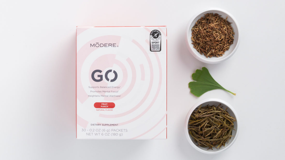 Modere Go Fruit Punch, lying next to three ingredients - bacopa plant, ginkgo leaves, and shatavari root.